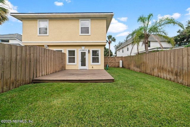 back of property featuring a wooden deck, stucco siding, a yard, and a fenced backyard