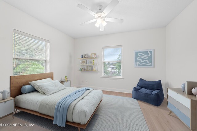 bedroom with ceiling fan, baseboards, and light wood-style floors