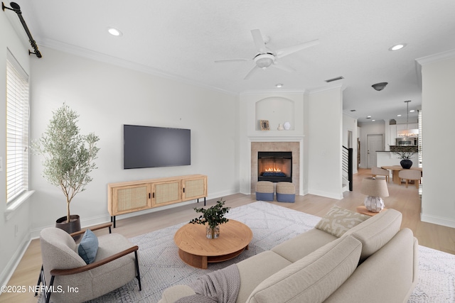 living room with baseboards, light wood-type flooring, ornamental molding, recessed lighting, and a fireplace