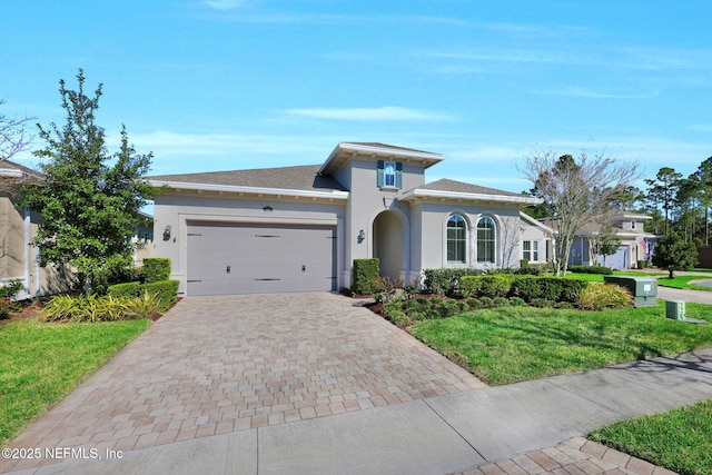 view of front facade featuring stucco siding, decorative driveway, a front yard, a shingled roof, and a garage