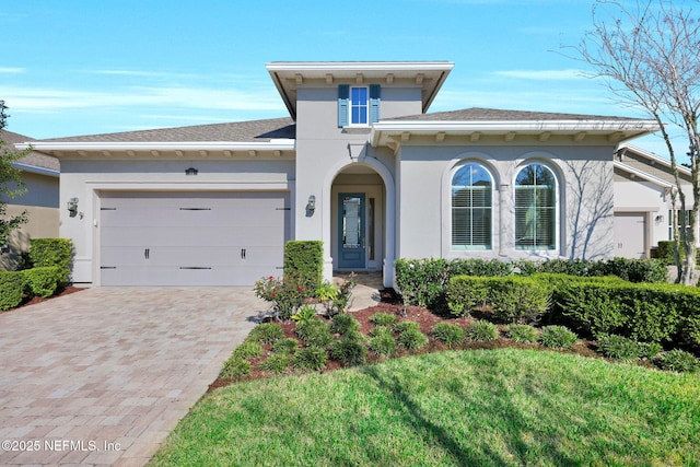 view of front of house with stucco siding, decorative driveway, roof with shingles, and an attached garage