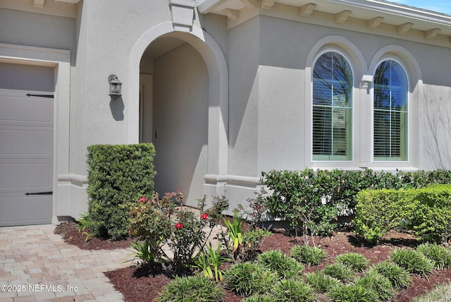 doorway to property with an attached garage and stucco siding