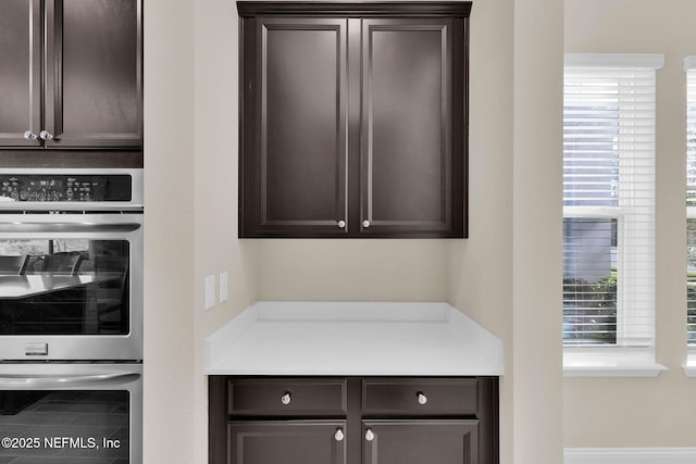 interior space featuring stainless steel double oven, dark brown cabinets, and light countertops