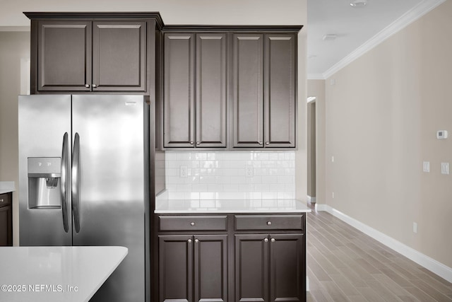 kitchen featuring decorative backsplash, ornamental molding, stainless steel fridge with ice dispenser, and light countertops