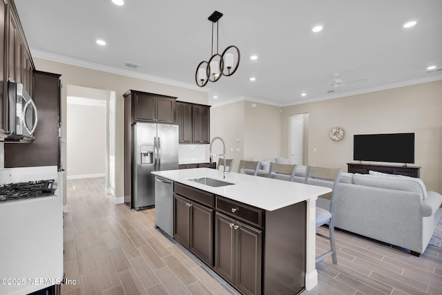 kitchen featuring wood tiled floor, dark brown cabinetry, a kitchen bar, appliances with stainless steel finishes, and a sink