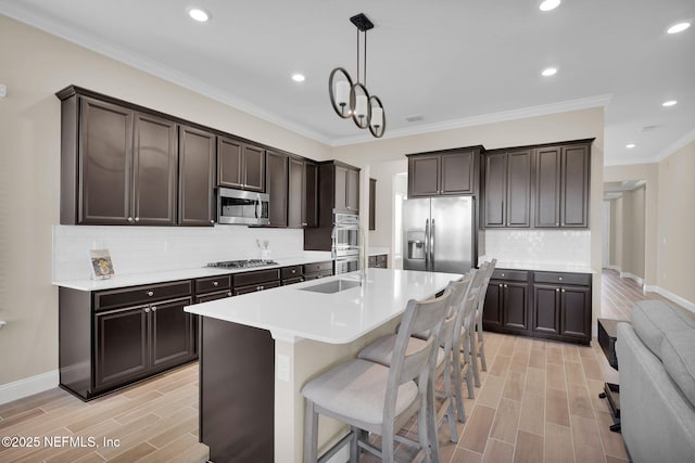 kitchen featuring wood finish floors, a sink, stainless steel appliances, light countertops, and dark brown cabinets