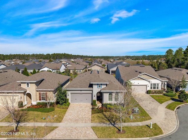 view of front of home with roof with shingles, an attached garage, stucco siding, decorative driveway, and a residential view