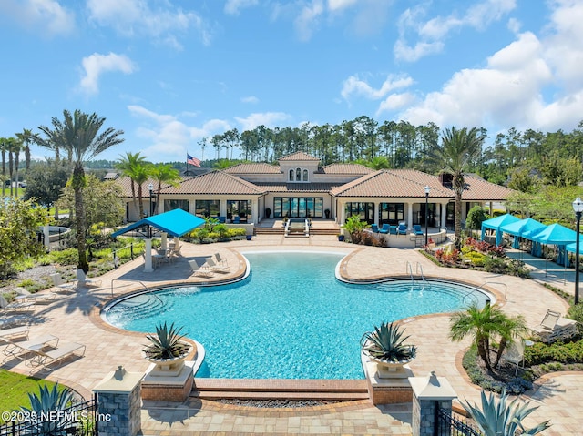 community pool with a patio and fence