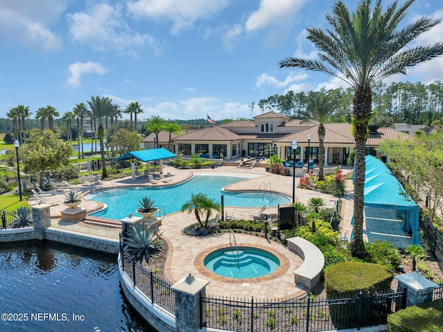 community pool featuring fence, a hot tub, and a patio area