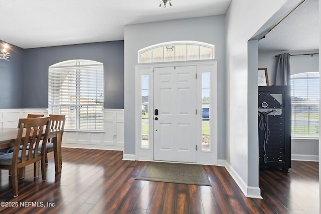 foyer with a decorative wall, wainscoting, baseboards, and wood finished floors