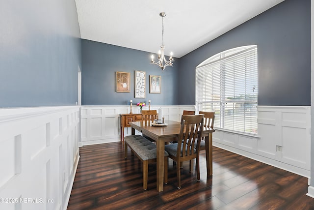 dining room with a wainscoted wall, a notable chandelier, and dark wood finished floors