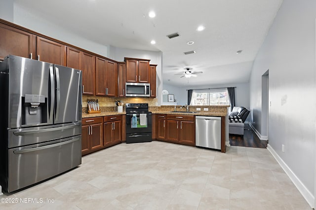 kitchen featuring visible vents, a sink, appliances with stainless steel finishes, a peninsula, and decorative backsplash