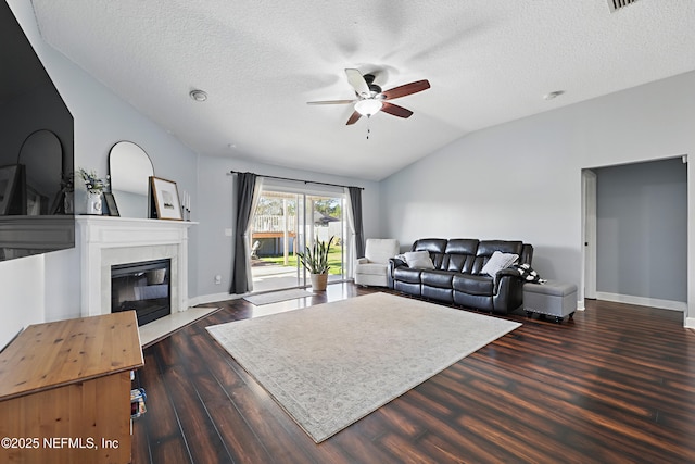 living room featuring a ceiling fan, wood finished floors, a tiled fireplace, and vaulted ceiling