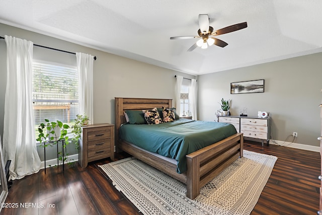 bedroom featuring baseboards, a raised ceiling, wood finished floors, and a ceiling fan