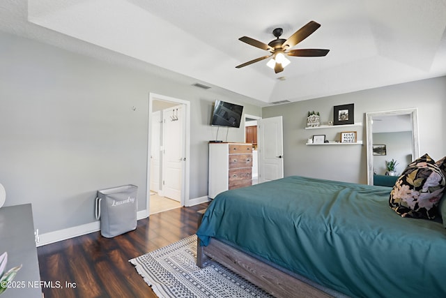 bedroom featuring a ceiling fan, wood finished floors, baseboards, visible vents, and a raised ceiling