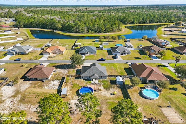 drone / aerial view with a residential view, a view of trees, and a water view