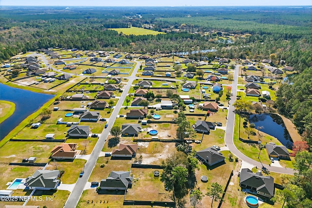 drone / aerial view featuring a residential view, a water view, and a view of trees