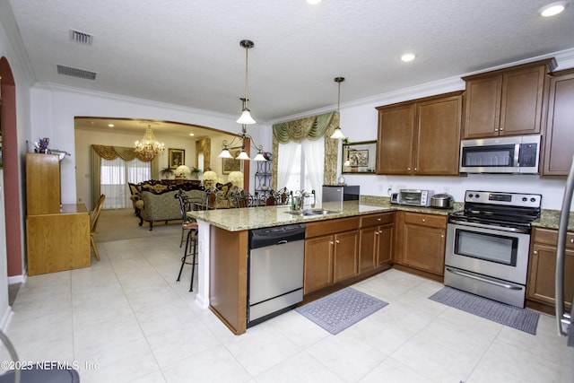 kitchen featuring visible vents, a peninsula, arched walkways, a sink, and appliances with stainless steel finishes