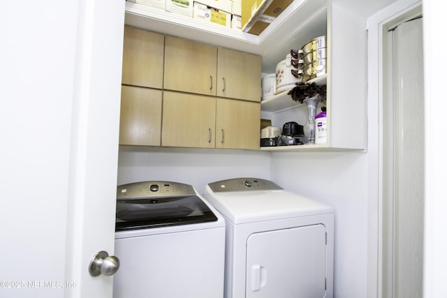 laundry room with washing machine and clothes dryer and cabinet space