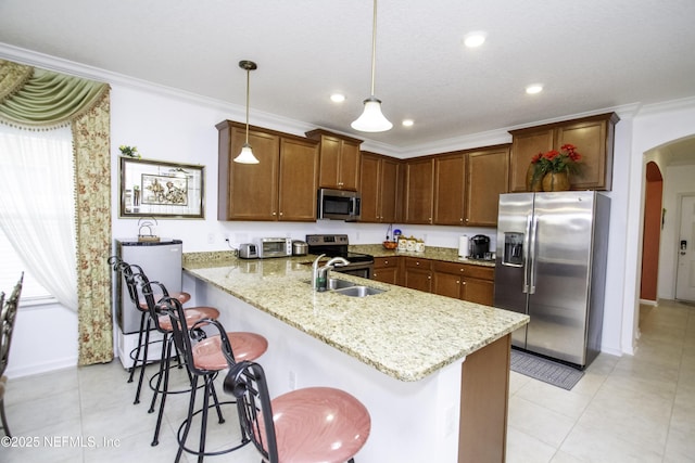 kitchen featuring a peninsula, arched walkways, a sink, appliances with stainless steel finishes, and crown molding