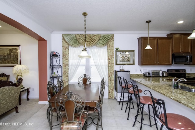 dining space with baseboards, a toaster, ornamental molding, light tile patterned flooring, and a textured ceiling