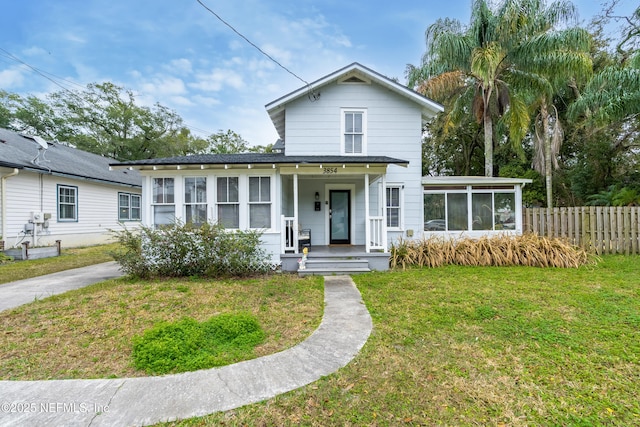 view of front of property featuring a shingled roof, a front lawn, fence, covered porch, and a sunroom