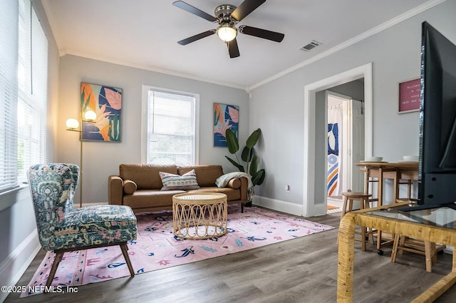 living room featuring visible vents, crown molding, baseboards, ceiling fan, and wood finished floors