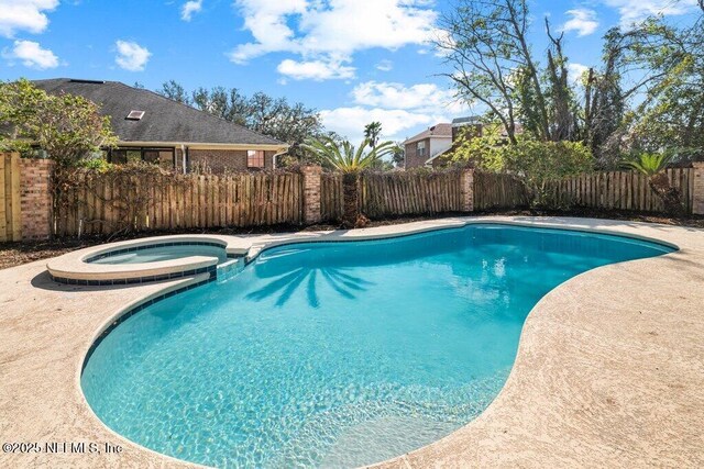 view of swimming pool with a fenced backyard and a pool with connected hot tub