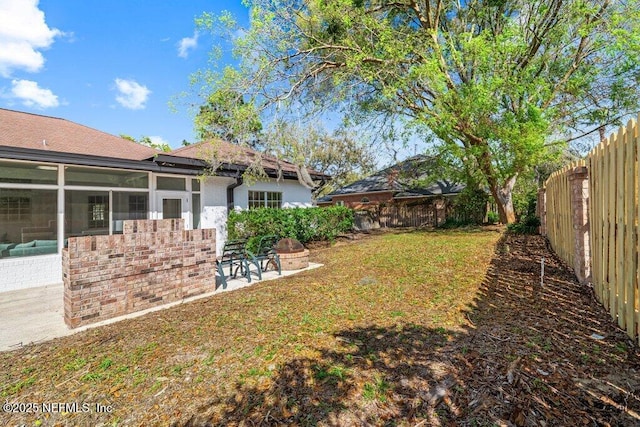 view of yard featuring a patio area, a fenced backyard, and a sunroom