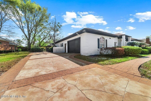 view of property exterior featuring stucco siding, driveway, a garage, and fence