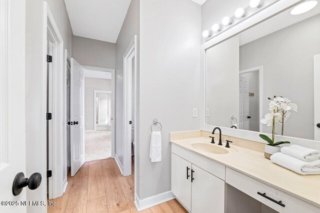 bathroom featuring vanity, wood finished floors, and baseboards