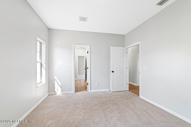 unfurnished bedroom featuring carpet flooring, baseboards, and visible vents