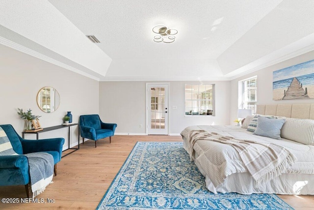 bedroom with wood finished floors, baseboards, visible vents, a textured ceiling, and a raised ceiling