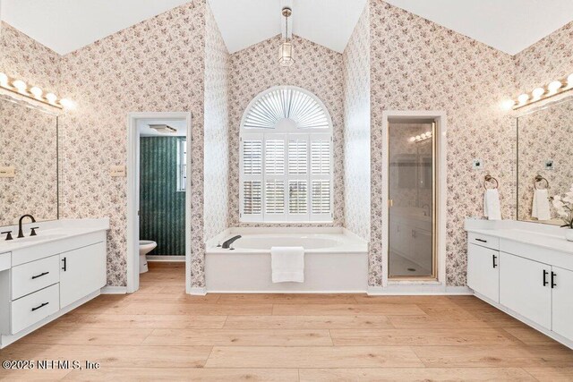 bathroom with wood finished floors, wallpapered walls, lofted ceiling, and a sink