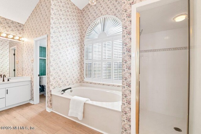 full bath featuring a healthy amount of sunlight, a stall shower, wallpapered walls, and a garden tub