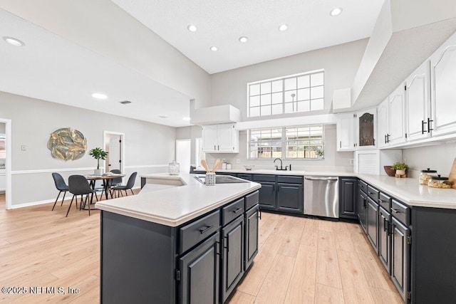 kitchen with a center island, dishwasher, light countertops, light wood-style floors, and white cabinets