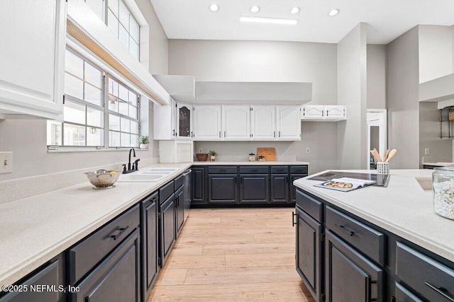 kitchen featuring light wood-type flooring, light countertops, recessed lighting, white cabinetry, and a sink