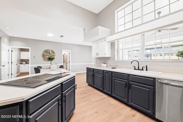 kitchen with a sink, black electric cooktop, stainless steel dishwasher, and light countertops