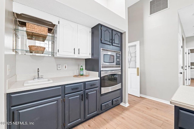 kitchen featuring visible vents, a sink, light countertops, light wood-style floors, and appliances with stainless steel finishes