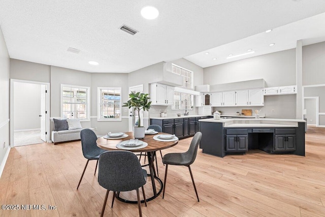 dining area featuring recessed lighting, visible vents, light wood finished floors, and a textured ceiling