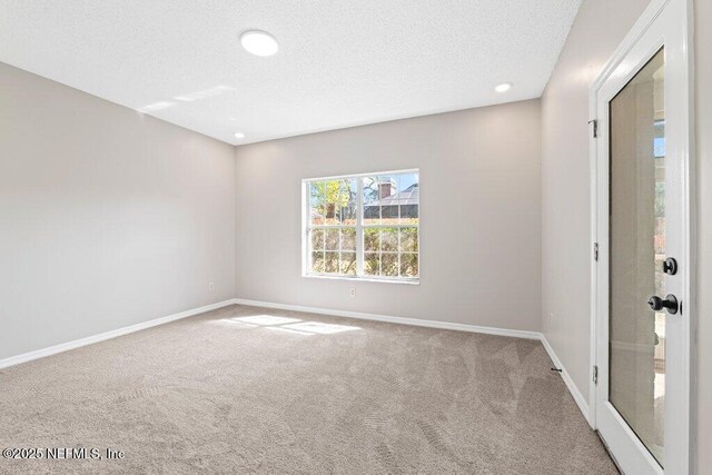 empty room with baseboards, carpet, and a textured ceiling