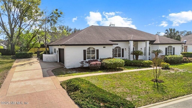 view of front of home featuring a front yard, fence, a shingled roof, stucco siding, and concrete driveway