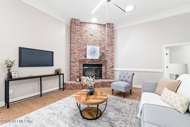 living room with a brick fireplace, wood finished floors, and ornamental molding