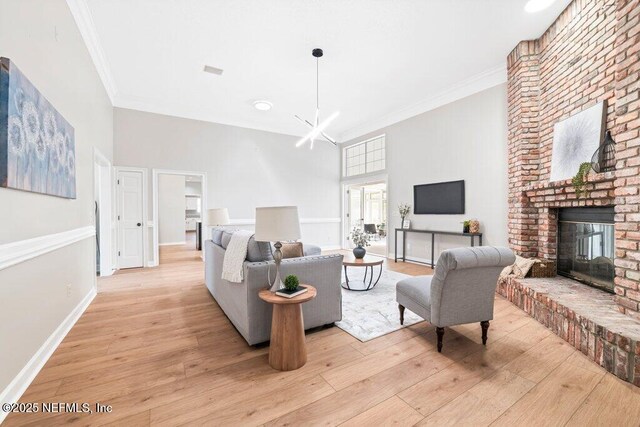 living area with crown molding, a fireplace, light wood-type flooring, and baseboards