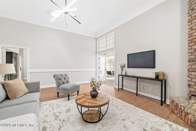 living area with an inviting chandelier, ornamental molding, baseboards, and wood finished floors