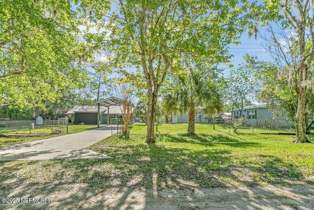 view of yard with concrete driveway and fence