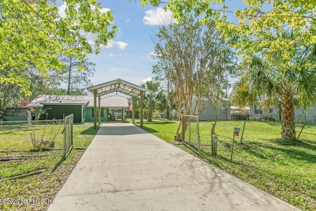 view of property's community featuring a lawn, concrete driveway, and fence