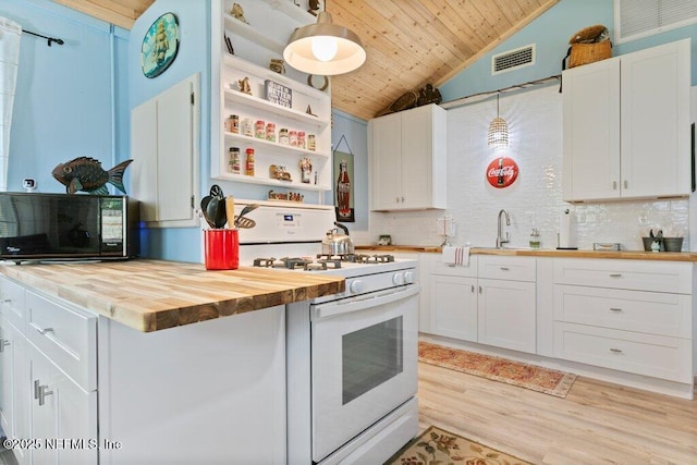 kitchen featuring black microwave, butcher block counters, white gas range oven, light wood-style floors, and open shelves