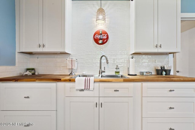 kitchen featuring decorative backsplash, white cabinets, a sink, and butcher block countertops