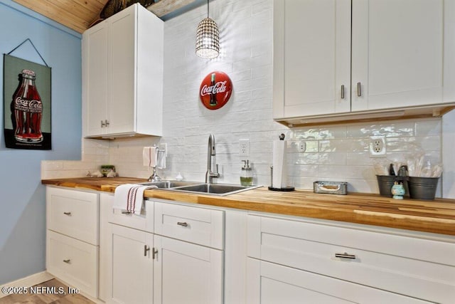 kitchen with decorative backsplash, white cabinetry, wood counters, and a sink